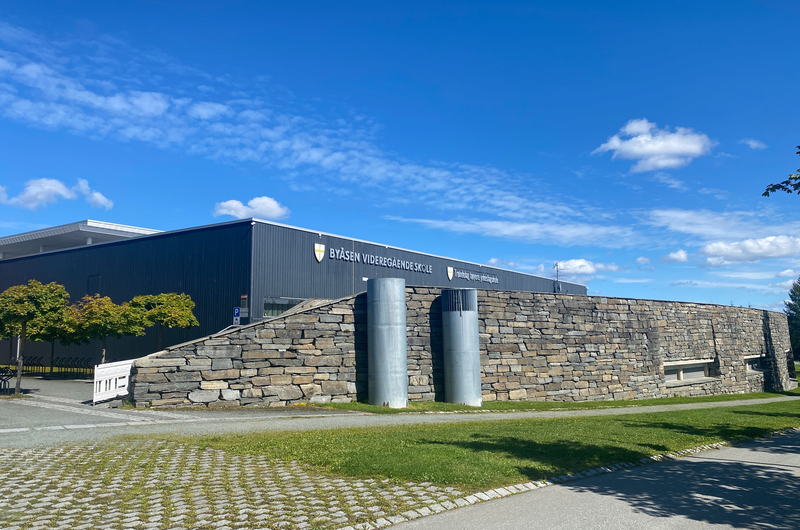 Skolebygget med blå himmel i bakgrunnen.